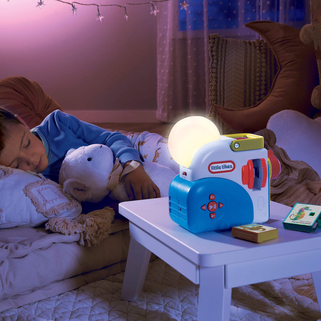 Child sleeping with a teddy bear next to a Little Tikes night light in a cozy bedroom.